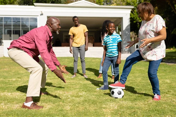 阳光灿烂的日子里 快乐的非洲裔美国多代家庭一起在前院踢足球 不变的家庭 周末和闲暇的概念 — 图库照片