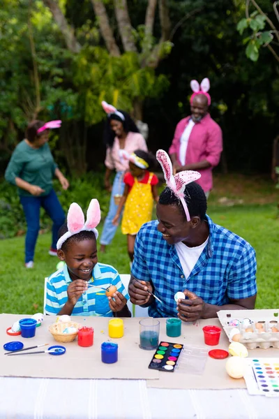 Feliz Niño Afroamericano Padre Pintando Huevos Pascua Mientras Familia Fondo —  Fotos de Stock