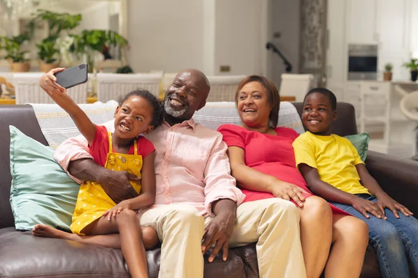非洲裔美国女孩在家里坐在沙发上 与兄长和祖父母私奔 不变的生活方式 聚会和休闲的概念 — 图库照片