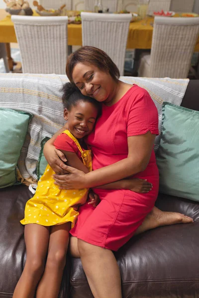 Een Glimlachende Afro Amerikaanse Seniorenvrouw Die Kleindochter Thuis Bank Omarmt — Stockfoto