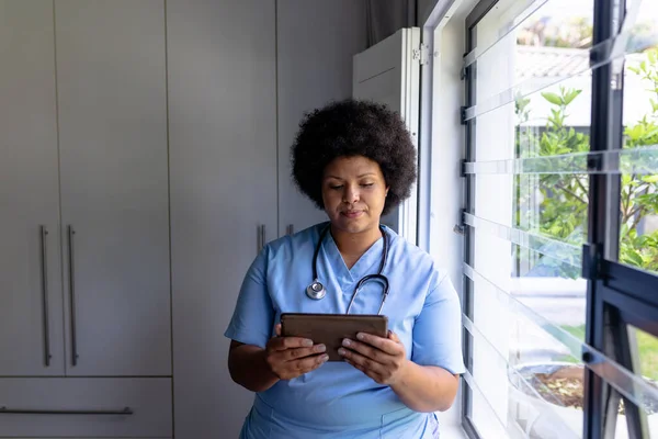 Afroamerykanka Połowie Dorosła Pielęgniarka Cyfrową Tabletką Stojąca Przy Oknie Szpitalu — Zdjęcie stockowe