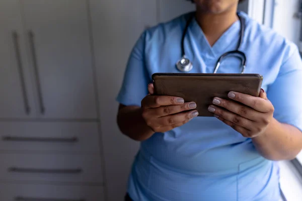 アフリカ系アメリカ人の成人女性看護師の中央部は病院でデジタルタブレットを使用している 変更されず医療従事者専門知識無線技術職業概念 — ストック写真