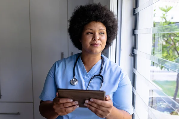 Χαμογελώντας Αφροαμερικανή Μεσήλικη Νοσοκόμα Που Κοιτάζει Αλλού Ενώ Κρατάει Ψηφιακή — Φωτογραφία Αρχείου