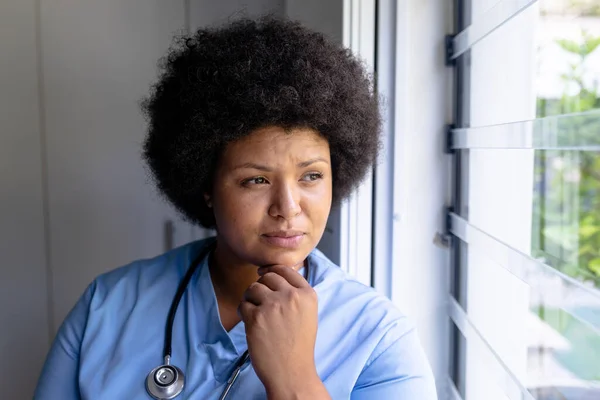 思考アフリカ系アメリカ人の成人女性看護師で顎を窓から見て手で 変化のない医療従事者熟考専門知識職業概念 — ストック写真
