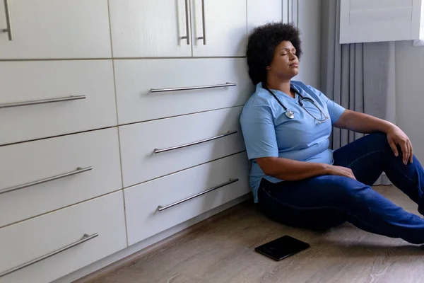 Enfermera Afroamericana Adulta Mediana Con Los Ojos Cerrados Sentada Suelo —  Fotos de Stock