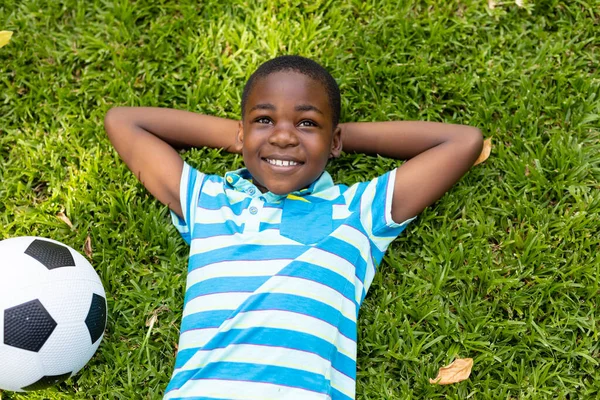 Smiling African American Boy Lying Hands Head Soccer Ball Grass — Stock Photo, Image