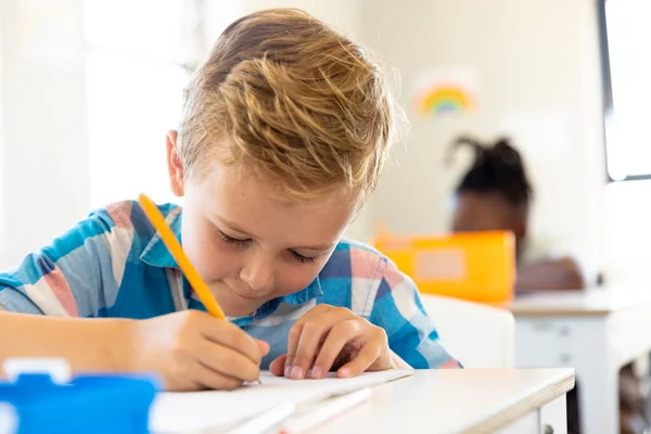 Close Cute Caucasian Elementary Schoolboy Writing Book While Sitting Desk — Stock Photo, Image