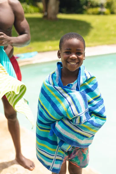 プールサイドで父親にタオルで包まれたアフリカ系アメリカ人の少年の笑顔の肖像画 変わらないライフスタイル子供時代楽しい家族レジャー週末のコンセプト — ストック写真