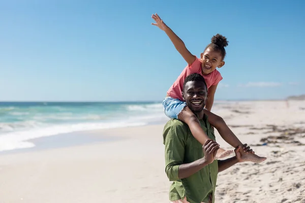 快乐的非洲裔美国女孩坐在父亲的肩上享受着海滩上的暑假 不变的家庭 生活方式 享乐及假日概念 — 图库照片