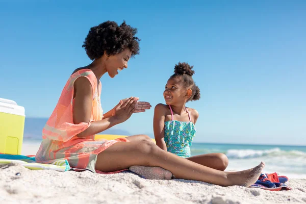 Szczęśliwa Afroamerykanka Nakładająca Krem Opalania Córkę Siedząc Plaży Słoneczny Dzień — Zdjęcie stockowe