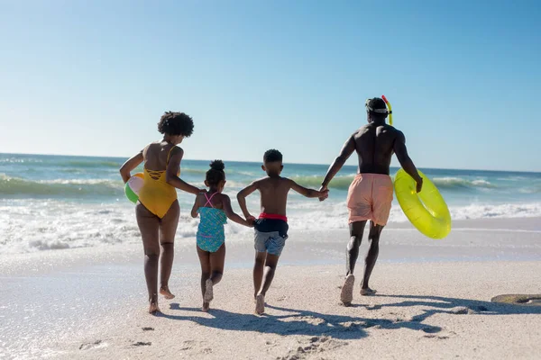 在阳光灿烂的日子里 非洲裔美国家庭手牵着手在海滩上奔跑的后视镜 不变的家庭 生活方式 享乐及假日概念 — 图库照片