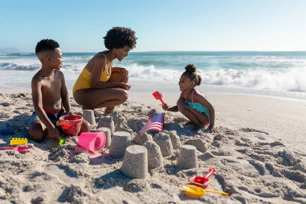 Afro Amerikaanse Moeder Hurkend Door Kinderen Zandkastelen Maken Het Strand — Stockfoto