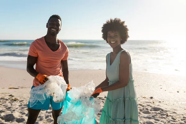 Portret Uśmiechniętej Afrykańskiej Pary Sprzątającej Plażę Plastikowych Odpadów Słoneczny Dzień — Zdjęcie stockowe