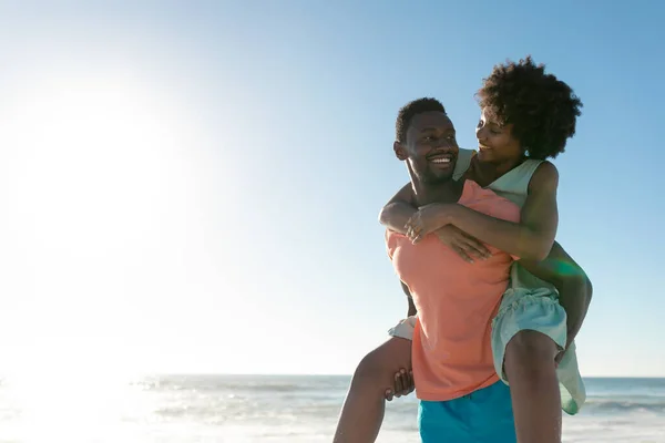 African American Man Giving Piggyback Girlfriend Beach Sky Copy Space — Stock Photo, Image