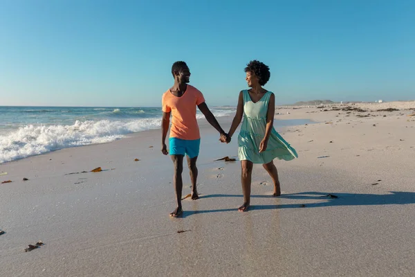 晴れた日には アフリカ系アメリカ人のカップルが青い空に向かって海岸を歩いています 変わらないライフスタイル愛団結休日の概念 — ストック写真