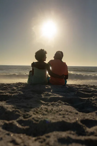 在海滩上 一对快乐的非洲裔美国夫妇抱着胳膊坐在沙滩上 相貌平平 不变的 不变的 不变的 不变的 不变的 不变的 不变的 — 图库照片