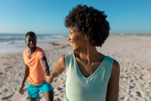 晴れた日にはビーチでボーイフレンドをリードしながら アフリカ系アメリカ人の女性が肩を上に見て笑顔 変わらないライフスタイル愛団結休日の概念 — ストック写真