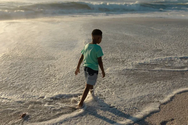 晴れた日にビーチで海岸に広がるアフリカ系アメリカ人の少年の完全な長さのリアビュー 変化のない子供時代楽しい休日のコンセプト — ストック写真