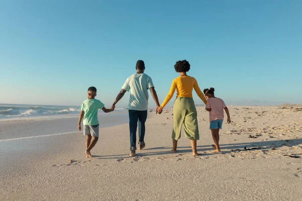 在阳光灿烂的日子里手牵着手在海滩上散步的非洲裔美国家庭的全长后视镜 不变的家庭 生活方式 享乐及假日概念 — 图库照片