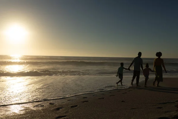 日落时 非裔美国家庭牵着手在沙滩上散步 并留有复制的空间 不变的家庭 生活方式 享乐及假日概念 — 图库照片