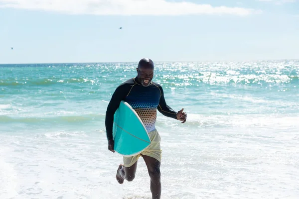 幸せなアフリカ系アメリカ人の老人は 海上を空に向かって走るサーフボードを持っている 変化のないアクティブなライフスタイル水生スポーツ休日の概念 — ストック写真