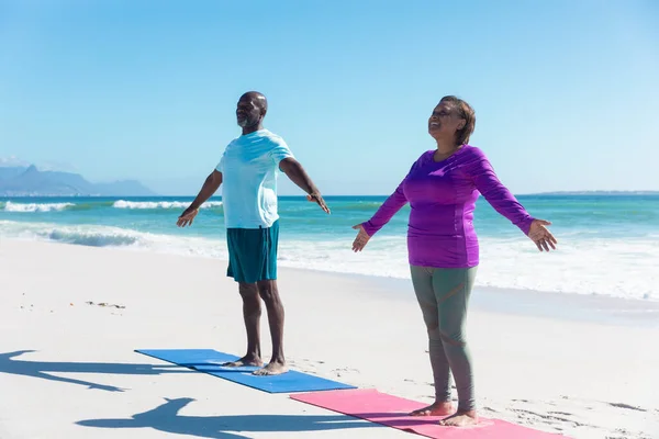 青の空を背景にビーチでヨガを練習しているアフリカ系アメリカ人の引退したシニアカップルの完全な長さ 変わらない愛団結フィットネス活動的なライフスタイルのコンセプト — ストック写真