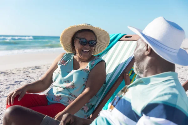 幸せなアフリカ系アメリカ人の高齢者のカップルがビーチで椅子を折りながら話しています 変わらない愛 ライフスタイル 楽しみと休日のコンセプト — ストック写真