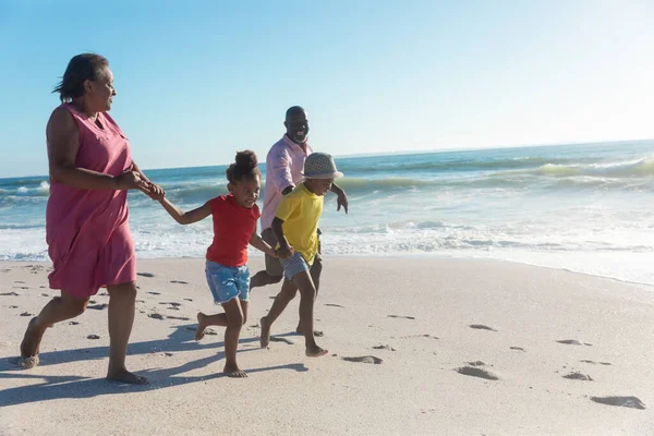 アフリカ系アメリカ人の祖父母と孫が晴れた日にビーチで一緒に走っています 変わることのない家族生活一緒に楽しむ休日の概念 — ストック写真