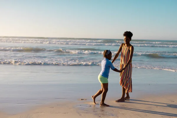 Африканская Американка Держит Молодую Женщину Руки Играя Пляже Против Ясного — стоковое фото
