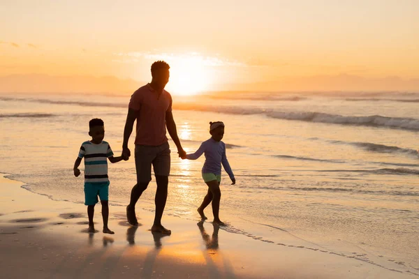 非裔美国人的年轻父亲牵着儿子和女儿的手在沙滩上与天空同行 Sunset Nature Unaltered Beach Childhood Family Totherness Lifestyle Enjoyment — 图库照片