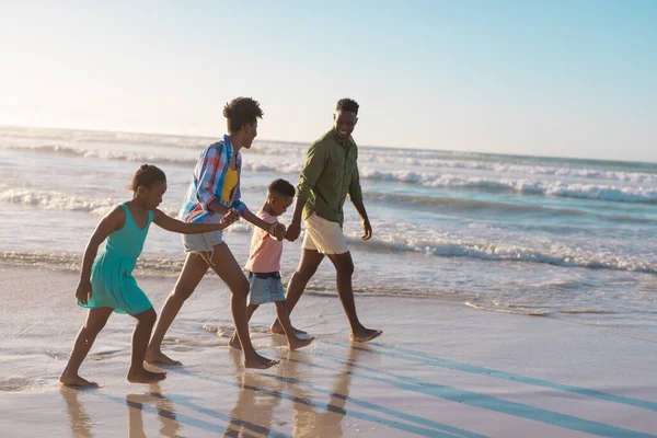 アフリカ系アメリカ人の若い両親は子供の手を取り 澄んだ空に向かってビーチを歩く コピースペース 変わらない 子供時代 一緒に ライフスタイル 楽しみ — ストック写真
