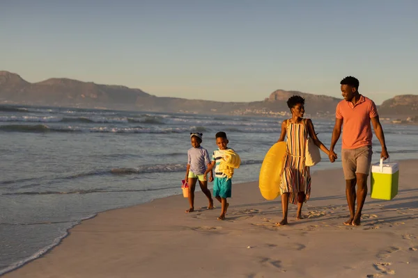 ビーチで子供と一緒に歩いている間にクーラーと毛布を持っているアフリカ系アメリカ人の若い両親 コピースペース 変わらない 子供時代 一緒に 楽しみと休日 — ストック写真