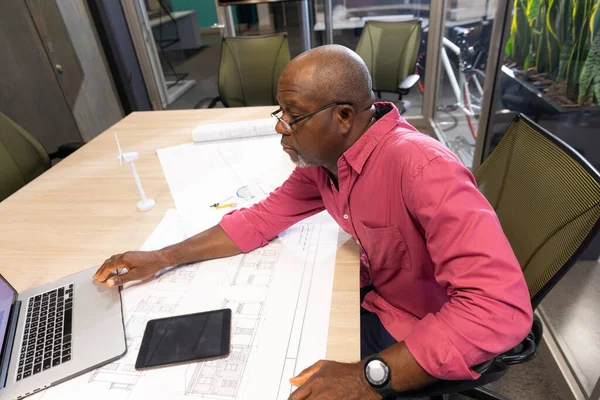 Mature African American Engineer Using Laptop While Sitting Blueprint Desk — Stock Photo, Image