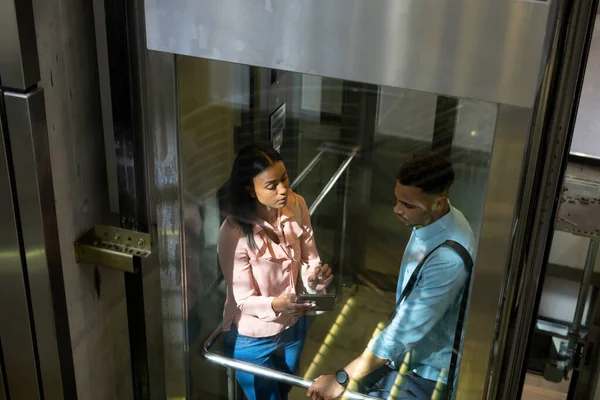 Vysoký Úhel Pohledu Kolegů Biracialu Diskutujících Tabletu Během Stání Výtahu — Stock fotografie