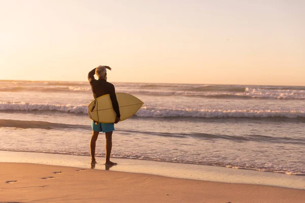 Visão Traseira Homem Sênior Afro Americano Carregando Prancha Surf Olhando — Fotografia de Stock