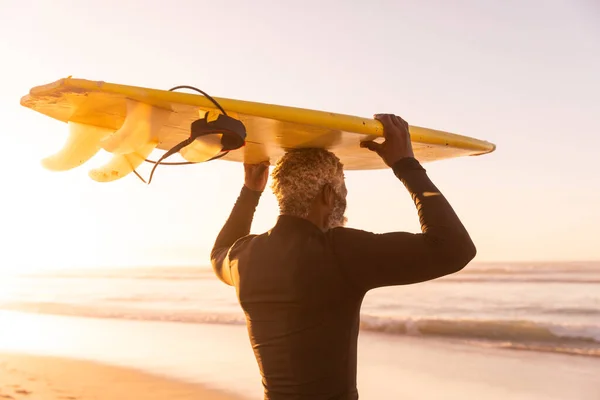 Afroameričan Starší Muž Nesoucí Surfovací Prkno Hlavě Zatímco Stojí Pláži — Stock fotografie