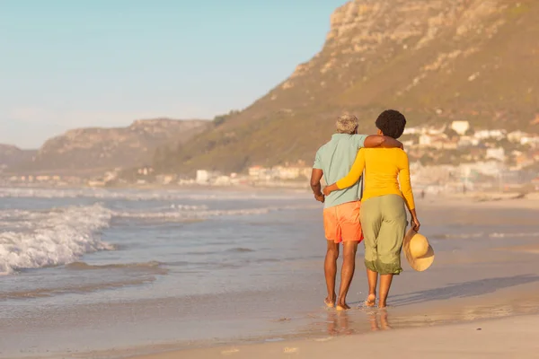日没時に澄んだ空に向かって海岸を歩く腕を持つアフリカ系アメリカ人のカップルの背面ビュー コピースペース 変わらない愛 楽しみと休日の概念 — ストック写真