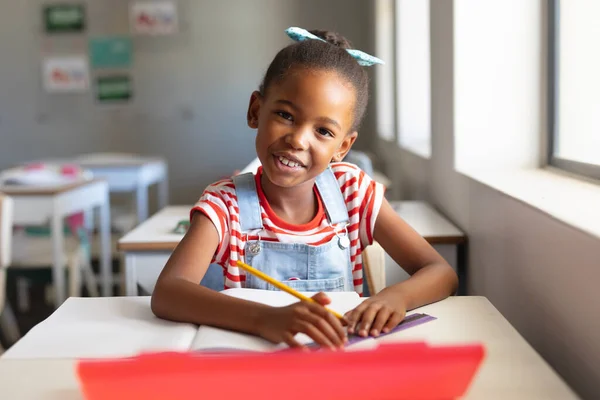 Portrait Smiling African American Elementary Schoolgirl Book Pencil Sitting Classroom — Stock Photo, Image