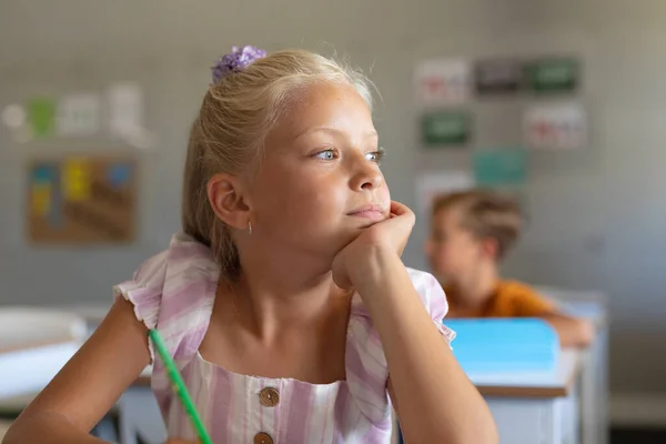 Figyelmes Kaukázusi Általános Iskolás Lány Kezével Állán Félrenéz Miközben Osztályteremben — Stock Fotó