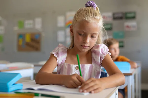 Studentessa Caucasica Delle Elementari Che Scrive Sul Libro Alla Scrivania — Foto Stock