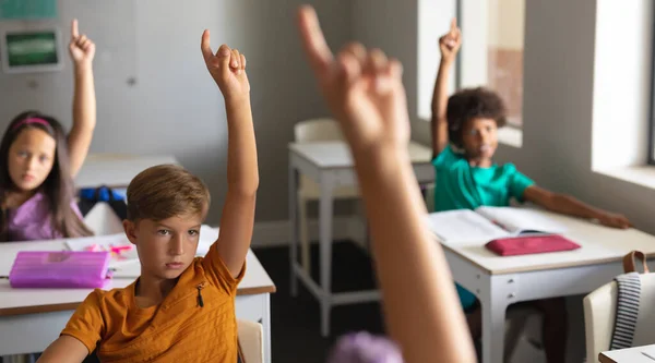 教室で授業中に手を挙げている多人種の小学生 変化のない教育学習知性子供時代学習学校の概念 — ストック写真