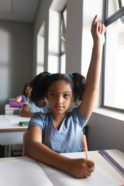 Niña Escuela Primaria Biracial Con Mano Levantada Sentada Escritorio Aula —  Fotos de Stock