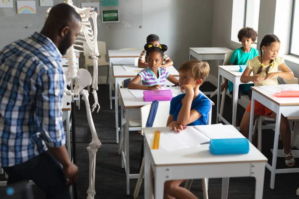 Африканский Молодой Учитель Американец Показывает Скелет Мультирасовым Школьникам Классе Изменений — стоковое фото
