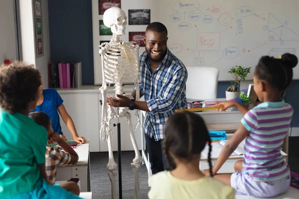 Feliz Afroamericano Joven Profesor Masculino Explicando Esqueleto Los Estudiantes Primaria —  Fotos de Stock