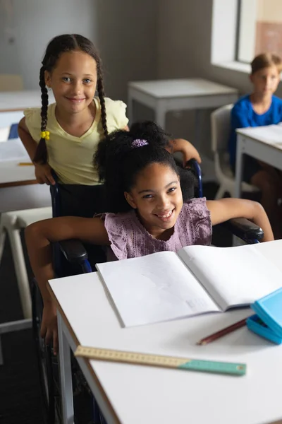 Portrait Caucasian Elementary Girl Standing Biracial Female Classmate Sitting Wheelchair — Stock Photo, Image