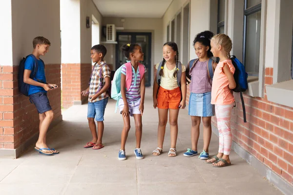 Okul Koridorunda Dikilirken Konuşan Çok Irklı Ilkokul Öğrencileri Değiştirilmemiş Eğitim — Stok fotoğraf