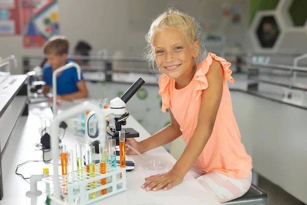 Porträtt Leende Kaukasiska Grundläggande Skolflicka Sitter Mikroskop Skolans Laboratorium Oföränderlig — Stockfoto