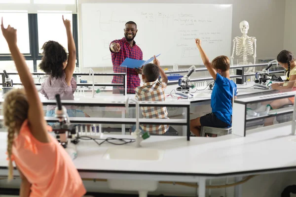 アフリカ系アメリカ人の若い男性教師が多人種の小学生に手を挙げて質問する 変更されていない教育 システム 学校の概念 — ストック写真
