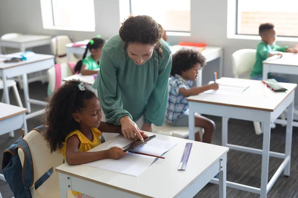 アフリカ系アメリカ人の小学生にデジタルタブレットを見せる若い白人女性教師 変化のない教育子供時代職業教育技術学習学校の概念 — ストック写真
