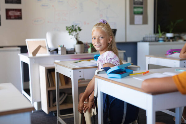 Portrait Smiling Caucasian Elementary Schoolgirl Sitting Desk Classroom Unaltered Education Stock Photo